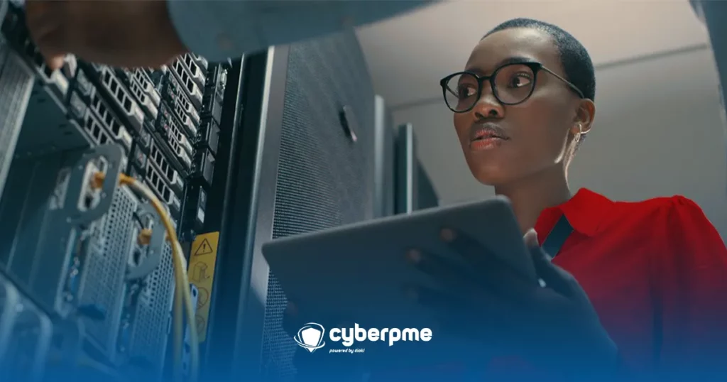 Technicienne en cybersécurité analysant les serveurs dans un centre de données après une cyberattaque, tenant une tablette.